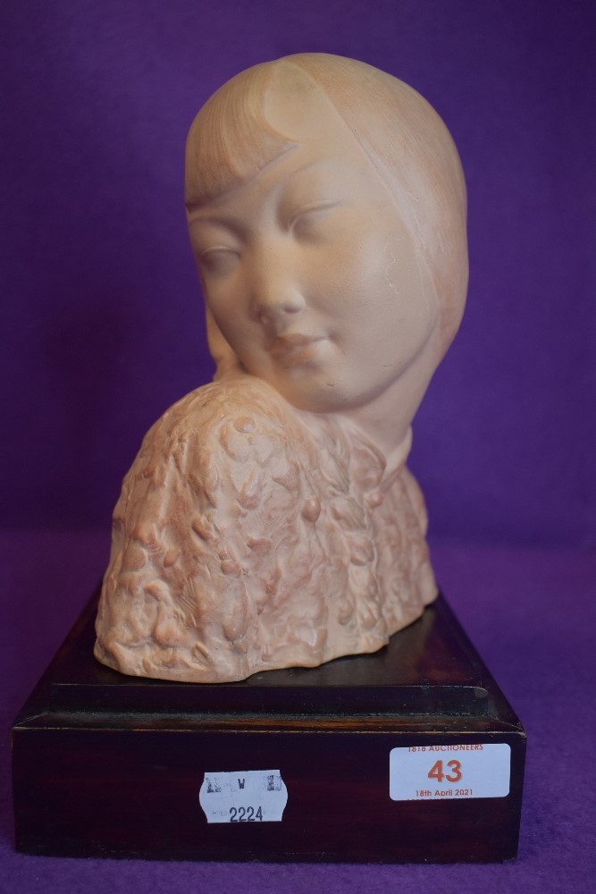 A bust mounted on plinth showing side profile of Geisha girl or similar.