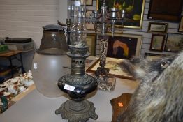 An antique oil burning lamp having ceramic well and brass fitments a wrought iron table lamp and