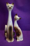 A pair of mid century ceramic Siamese cat figurines.