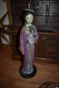 An antique plaster cast figure of a Japanese Geisha holding a parrot 38cm tall having historic