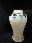 A Ruskin pottery vase having gold and cream lustre ground with green grape vine border to neck,