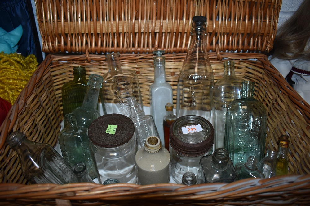 A wicker picnic basket containing a selection of vintage bottles and jars including poison bottles.