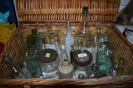 A wicker picnic basket containing a selection of vintage bottles and jars including poison bottles.