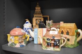 An array of novelty tea pots including cottages and more.