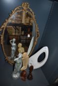 A metal framed gilt wall mirror and a selection of modernist figures and wooden items.