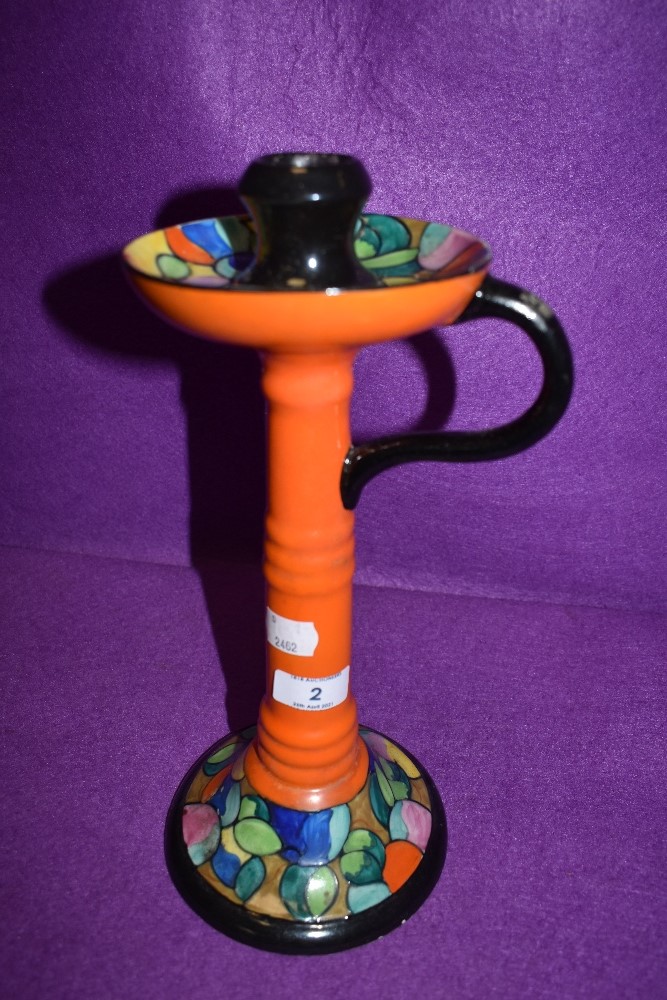 A large Bursley ware candlestick holder having vibrant orange ground and tube lined design