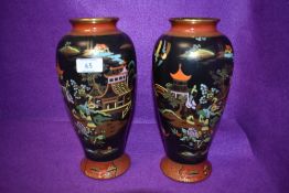 A pair of Carlton ware vases having black ground with orange accents,oriental styled scenes and gilt