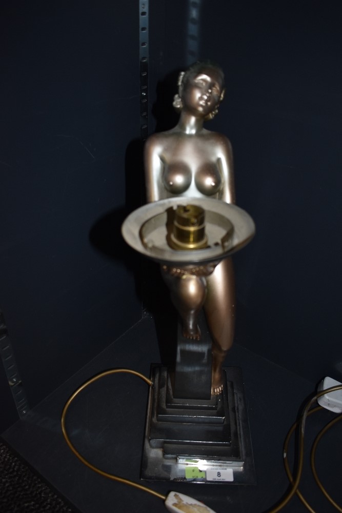 An art deco table lamp depicting seated nude lady in gold holding bowl, having contrasting black