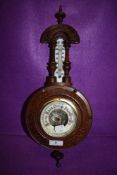 A vintage wall mounted barometer having carved wooden case and finial to top.