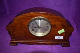 A wood cased mantle clock having inlaid detail.