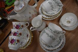 A mixture of cups and saucers and a tea pot,various designs and styles.
