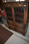 An Old Charm or similar bookcase, leaded glass fronted with linen fold double cupboard under,