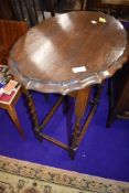An early 20th Century oak twist frame occasional table having shaped top, width approx. 63cm