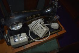 A vintage Singer electric sewing machine in the traditional style , with case