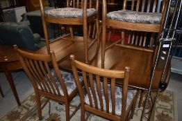 A modern Ercol dining table and six (four plus two) rail back dining chairs, mid colour, in very