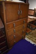 A mid 20th Century oak bedroom cabinet having double cupboard over four long drawers, metal Deco