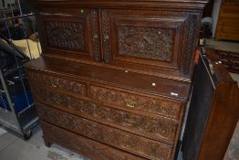 A 19th Century oak cabinet on two over three drawers, in the Continental style having carved panel