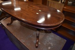 A reproduction mahogany coffee table having oval top with ornate column and scroll feet, width