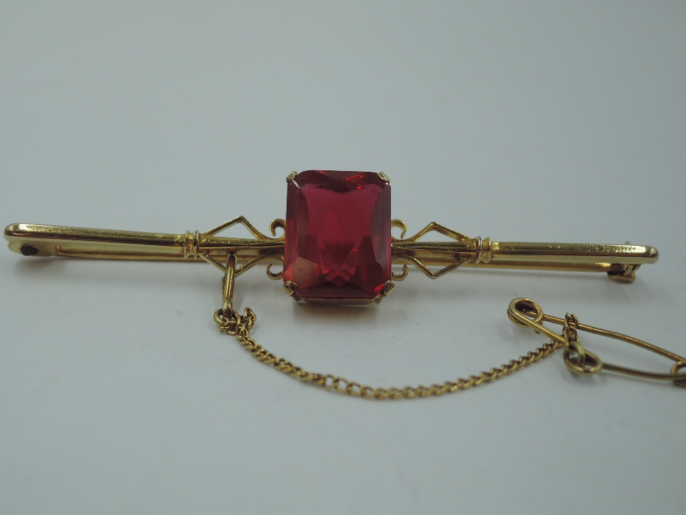 A yellow metal bar brooch stamped 9ct having a central ruby style rectangular stone, approx 4.6g - Image 2 of 3