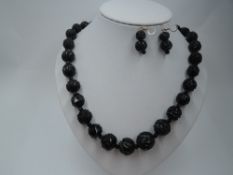 A string of Whitby Jet carved beads of graduated spherical form with small rough carved spacers,