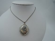An HM silver oval locket having engraved scroll decoration on a white metal fancy link chain, approx