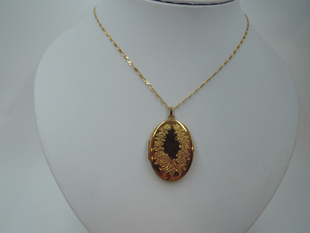 A 9ct gold oval locket having engraved floral decoration to front, on a 9ct gold figaro chain,