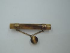 A vintage tigers eye bar brooch having yellow metal bands with chain connecter to tigers eye bead