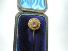A cased yellow metal stick pin stamped 15ct having a central powder blue sapphire
