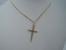 A 9ct gold cross with bark effect decoration on a gold plated chain