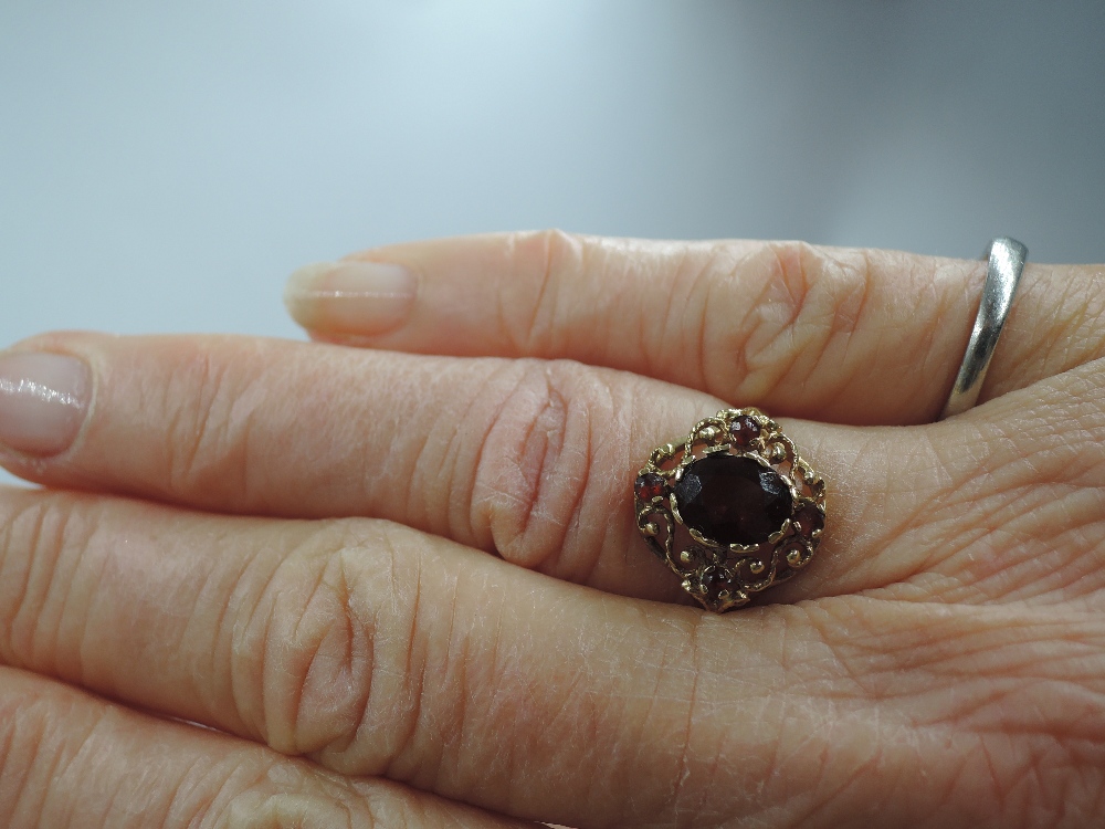 A lady's dress ring having a central garnet in an open decorative border on a 9ct gold loop, size - Image 2 of 2