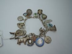 A white metal charm bracelet stamped silver having padlock clasp and sixteen charms including