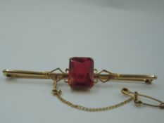 A yellow metal bar brooch stamped 9ct having a central ruby style rectangular stone, approx 4.6g