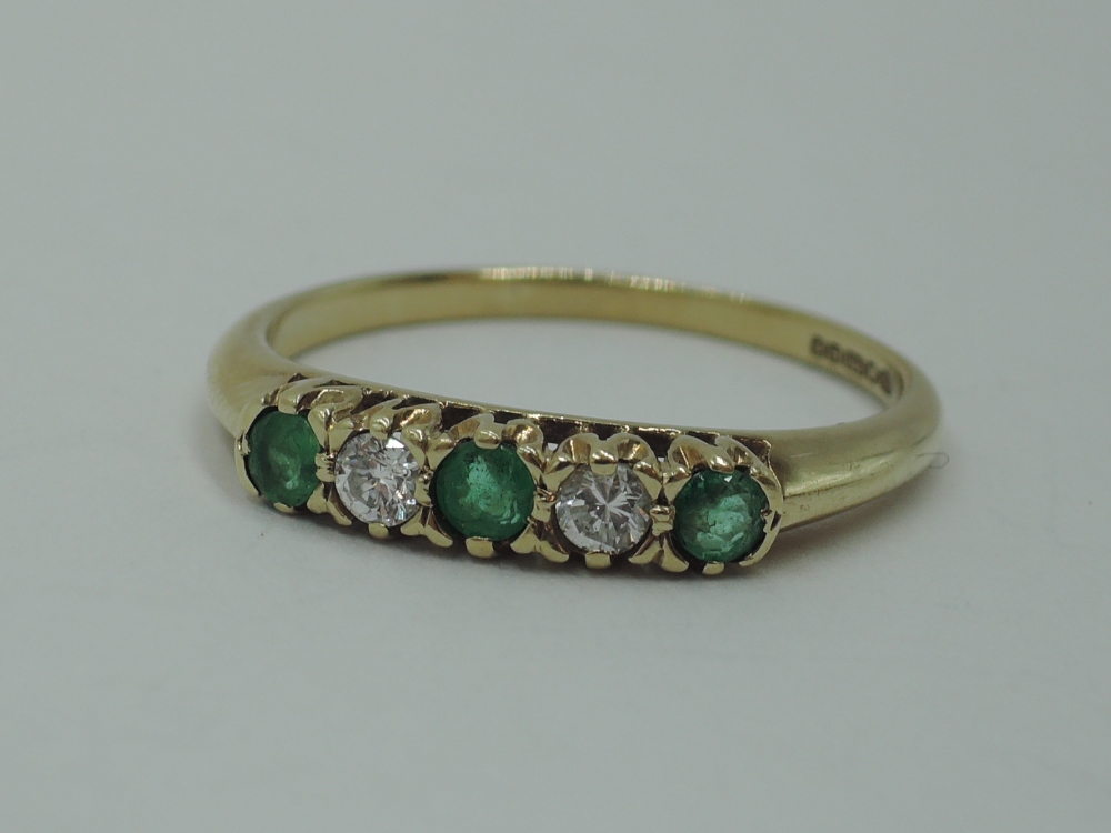 A five stone diamond and emerald dress ring having three emeralds interspersed by two diamonds in