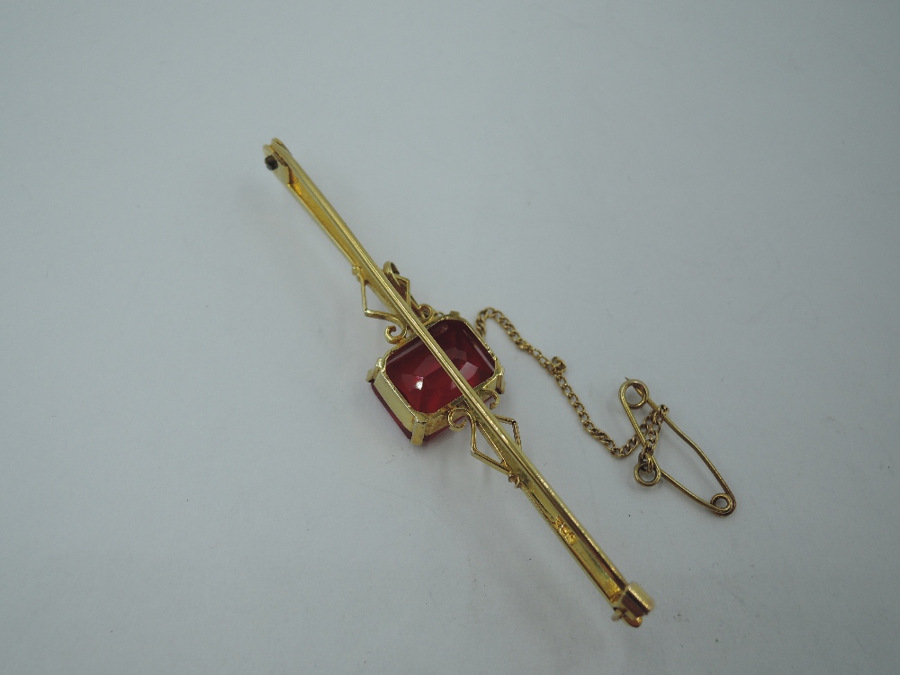 A yellow metal bar brooch stamped 9ct having a central ruby style rectangular stone, approx 4.6g - Image 3 of 3