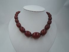 A string of graduated cherry amber beads of graduated oval form, approx 72g & 22'