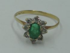 A cluster dress ring having an oval emerald style stone within a surround of cubic zirconia on a 9ct