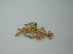 A Victorian yellow metal brooch stamped 15ct modelled as a tied posy of flowers having seed pearl