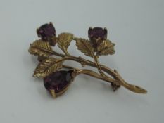 A 9ct gold brooch modelled as a sprig of flowers having a trio of amethyst style stones, approx 5.
