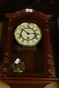 A wooden cased wall mounted clock with key.