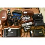 A collection of vintage cameras and binoculars including Kodak Instamatic, Kodak Synchro-Compur