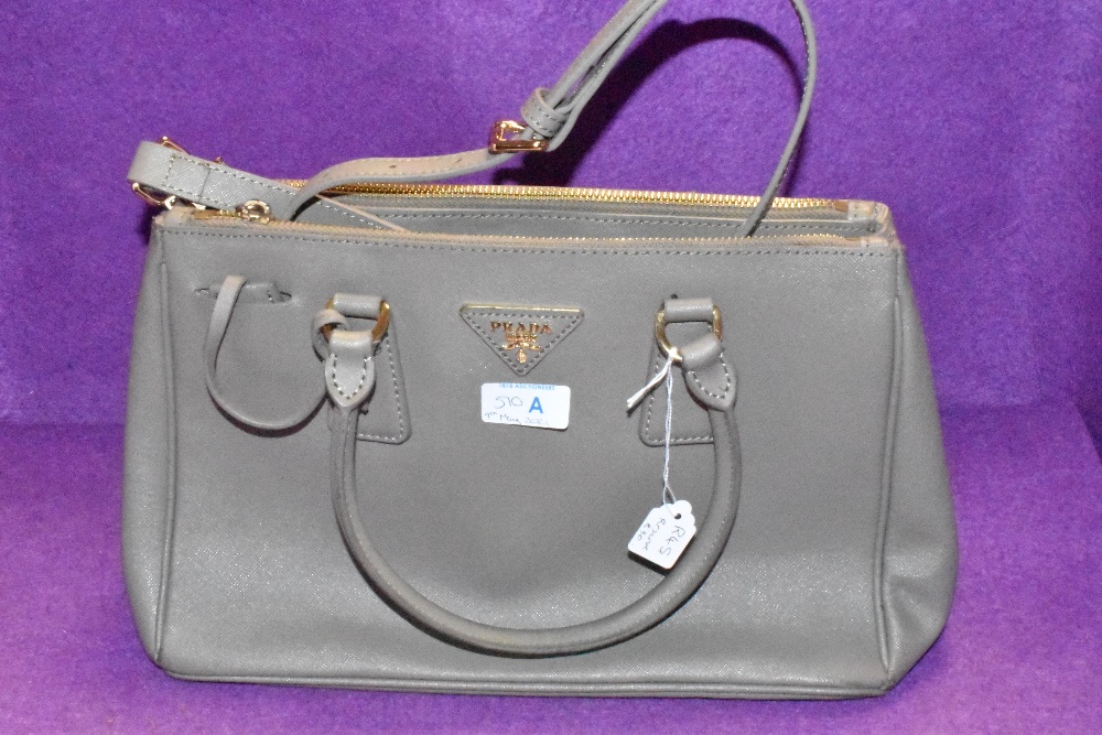 A grey handbag bearing Prada name,dust cover included.