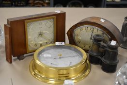 Two vintage mantle clocks a set of binoculars and barometer.