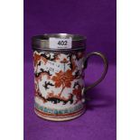 An antique hard paste porcelain ale or similar mug having Imari styled palette HM white metal rim