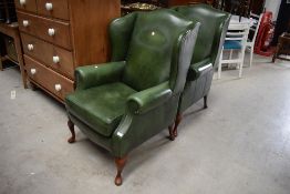 A pair of wing backed olive green leather arm chairs