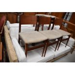 A set of four vintage teak or similar dining chairs having ply backs and upholstered seats