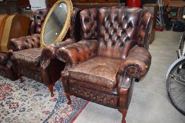 A pair of Gentleman's club style button back leather wing back armchairs, worn patina, possibly