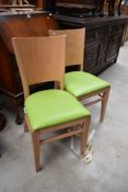 A pair of beech and ply kitchen dining chairs, having lime green vinyl seats, labelled Pineapple