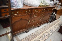 A period oak dresser base having brass drop handles, canted corners and bracket feet, width