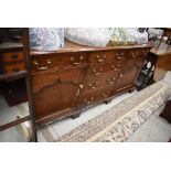 A period oak dresser base having brass drop handles, canted corners and bracket feet, width