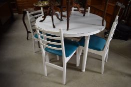 A mid century circular dining table having set of four teal seated ladder back chairs